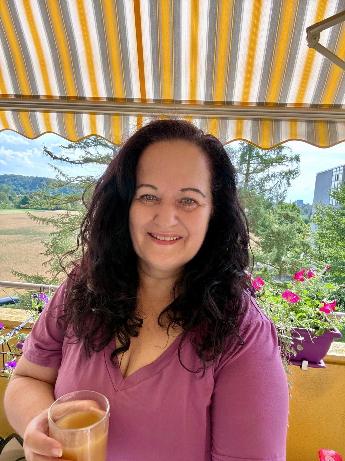 Yvonne mit einem Glas Cellagon auf ihrem Balkon