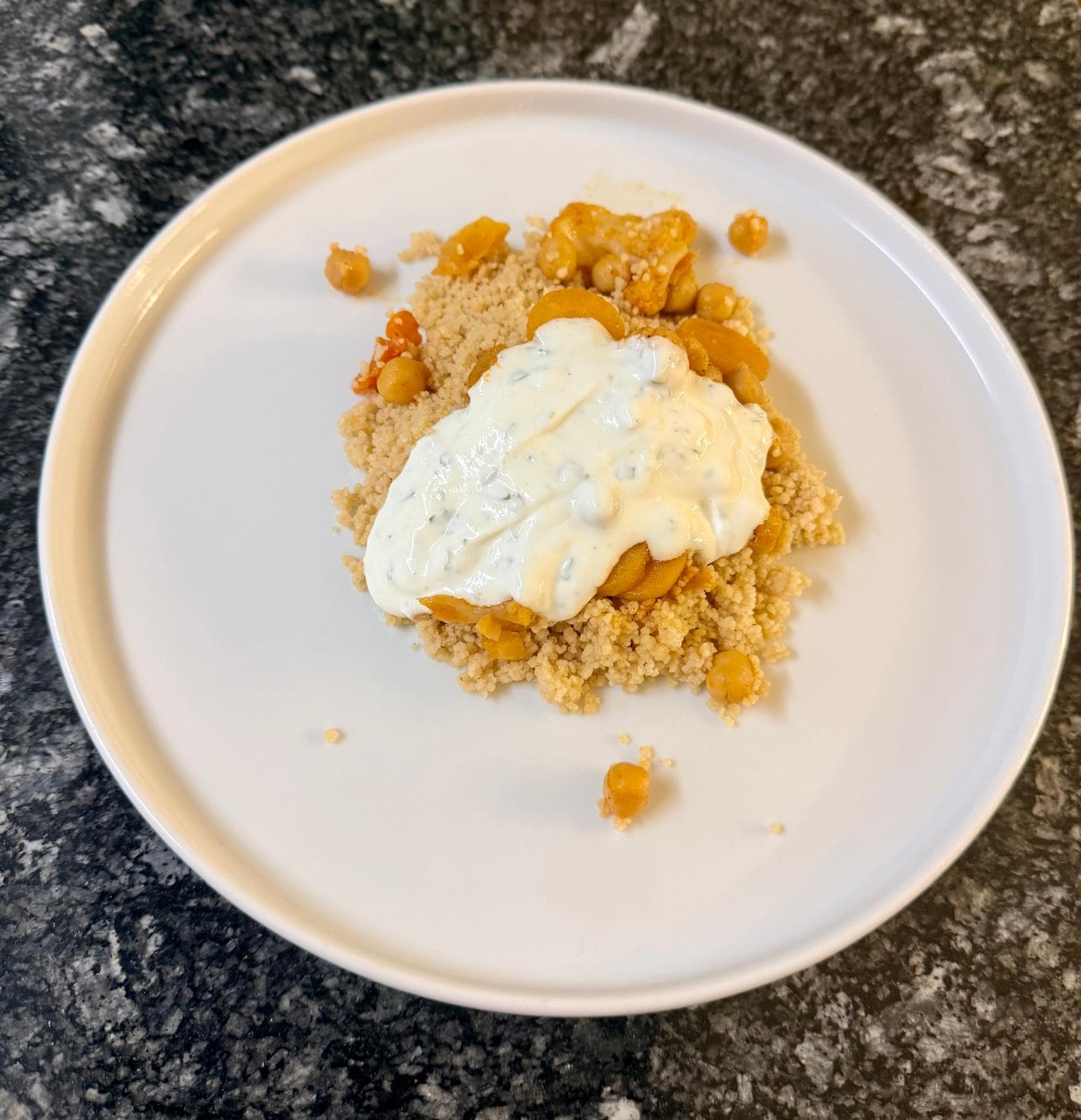Orientalische Gemüsepfanne mit Kichererbsen, Blumenkohl und Karotten, serviert mit Couscous und cremigem Zitronenjoghurt.