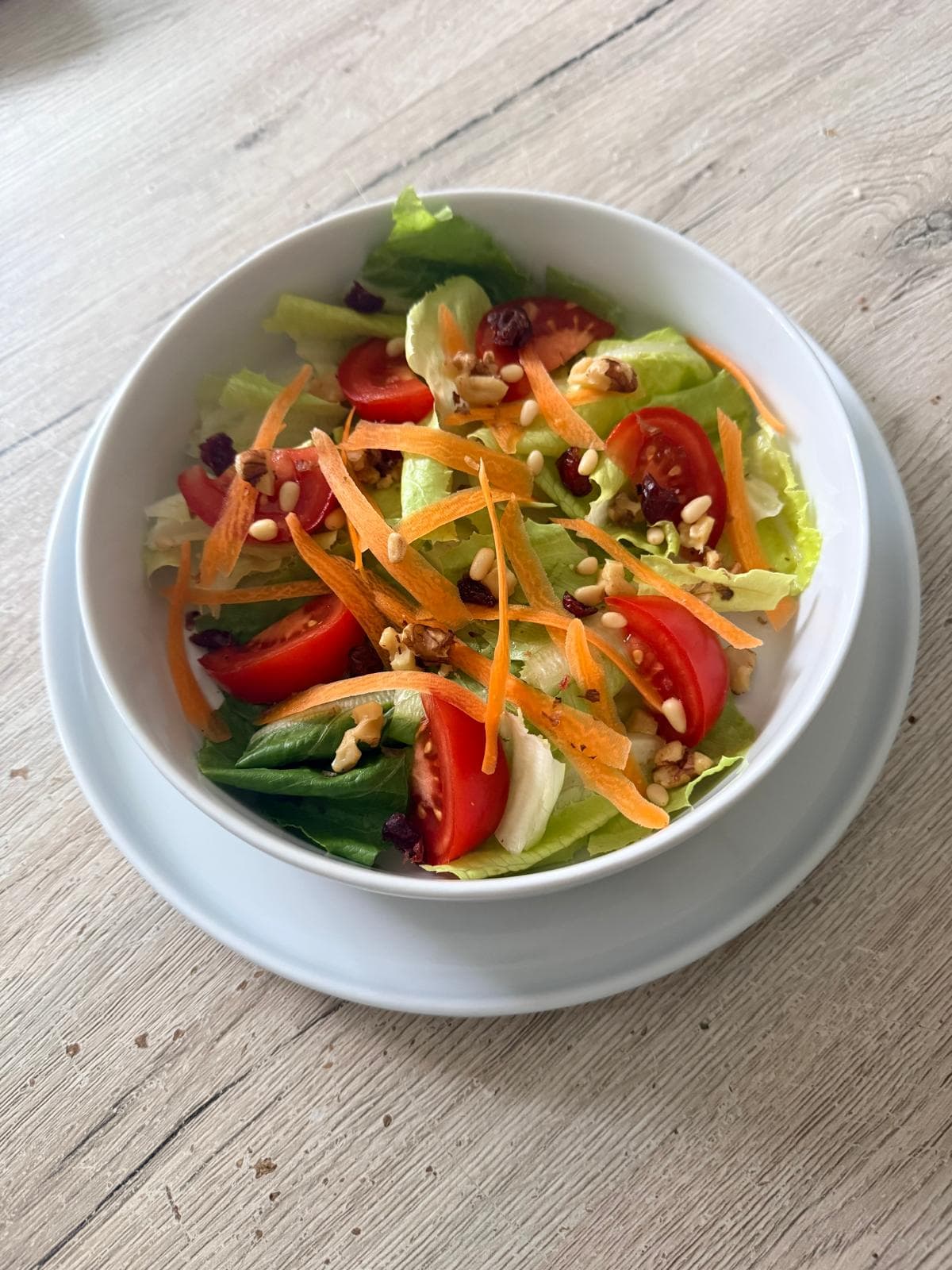 Frischer gemischter Salat mit Tomaten, Rüebli, Nüssen und Kernen als Beispiel für eine abwechslungsreiche Ernährung.